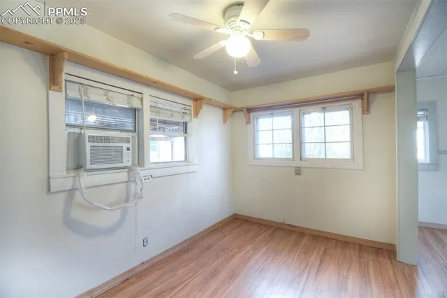 a view of empty room with wooden floor and fan