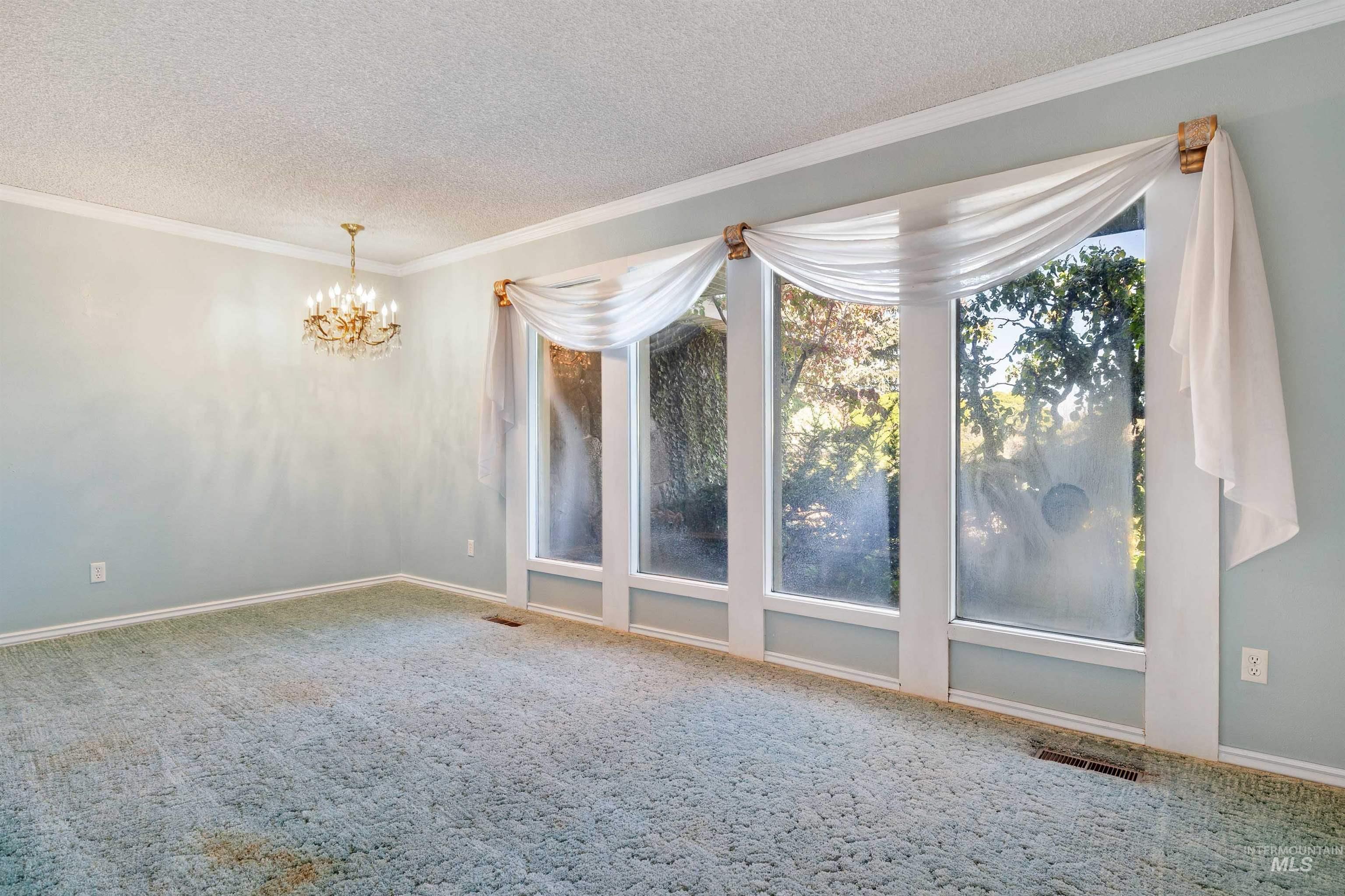 415 West 300 South Heyburn, ID 83336 - Photo 16 of 50 Empty room featuring crown molding, carpet floors, a chandelier, and a textured ceiling