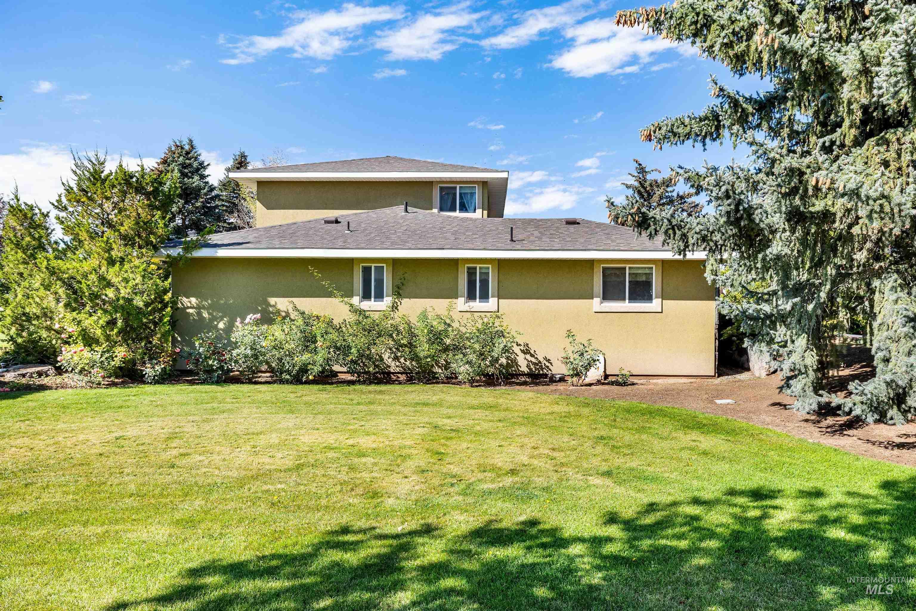 415 West 300 South Heyburn, ID 83336 - Photo 31 of 50 Rear view of property featuring a lawn, stucco siding, and roof with shingles