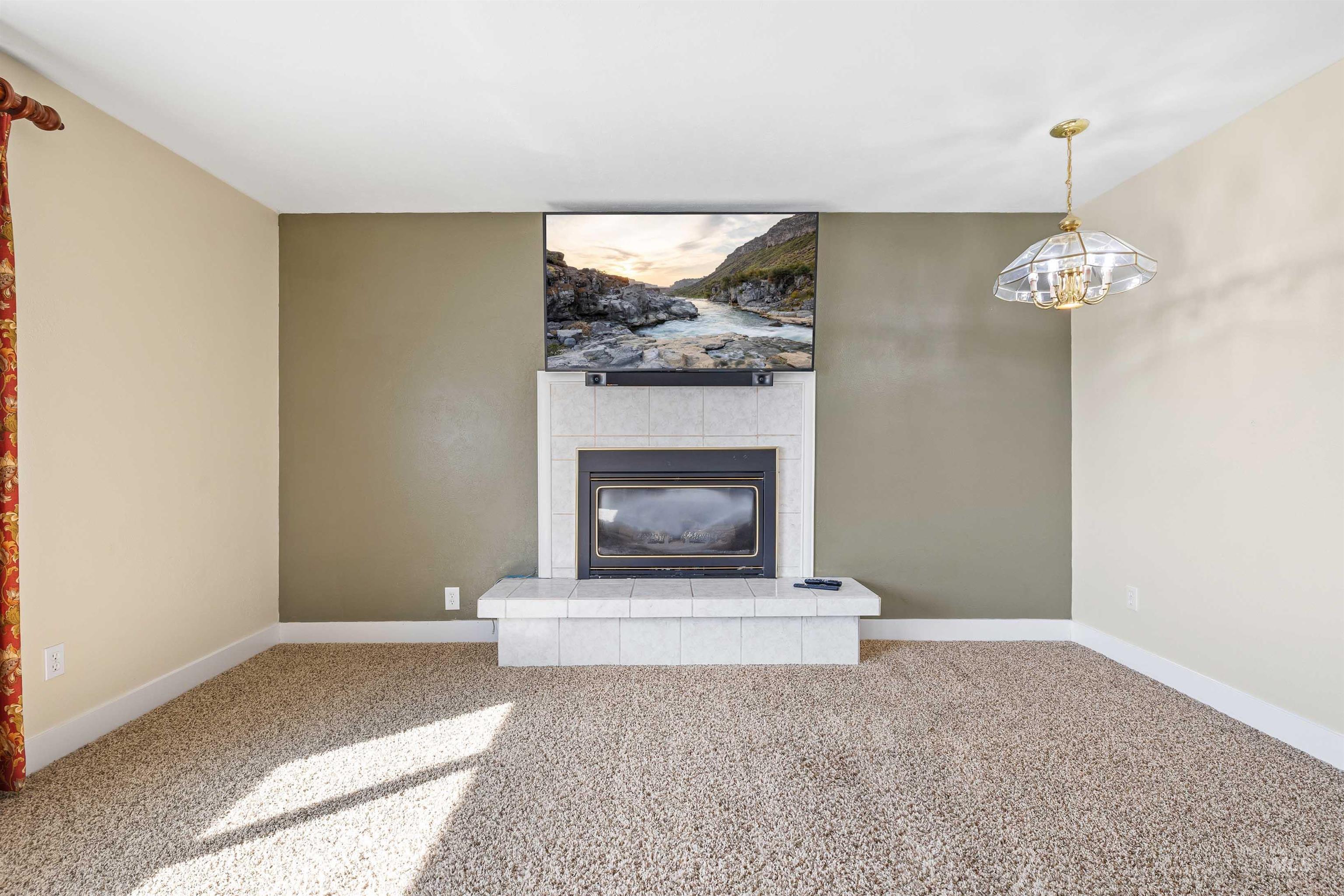 415 West 300 South Heyburn, ID 83336 - Photo 8 of 50 Unfurnished living room with carpet, a tiled fireplace, and a chandelier