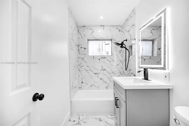 a bathroom with a sink and mirror with toilet