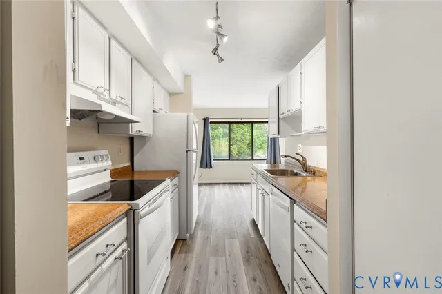 a kitchen with granite countertop a sink a counter space appliances and cabinets