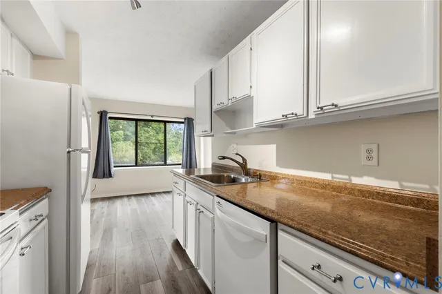 a kitchen with granite countertop stainless steel appliances a sink window and cabinets