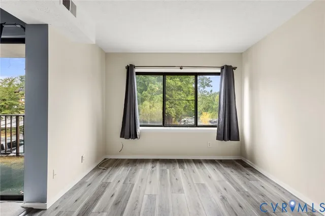 an empty room with wooden floor and windows