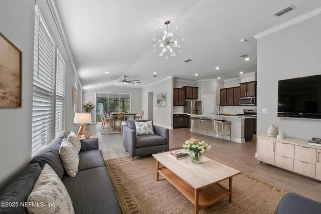 a living room with furniture kitchen view and a flat screen tv