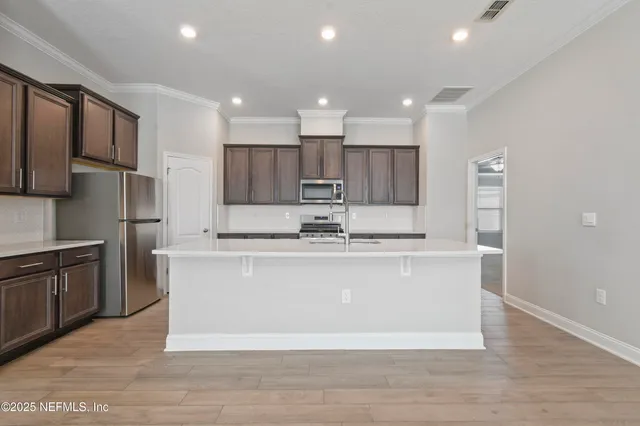 a large kitchen with stainless steel appliances granite countertop a large counter top a stove a sink and a refrigerator