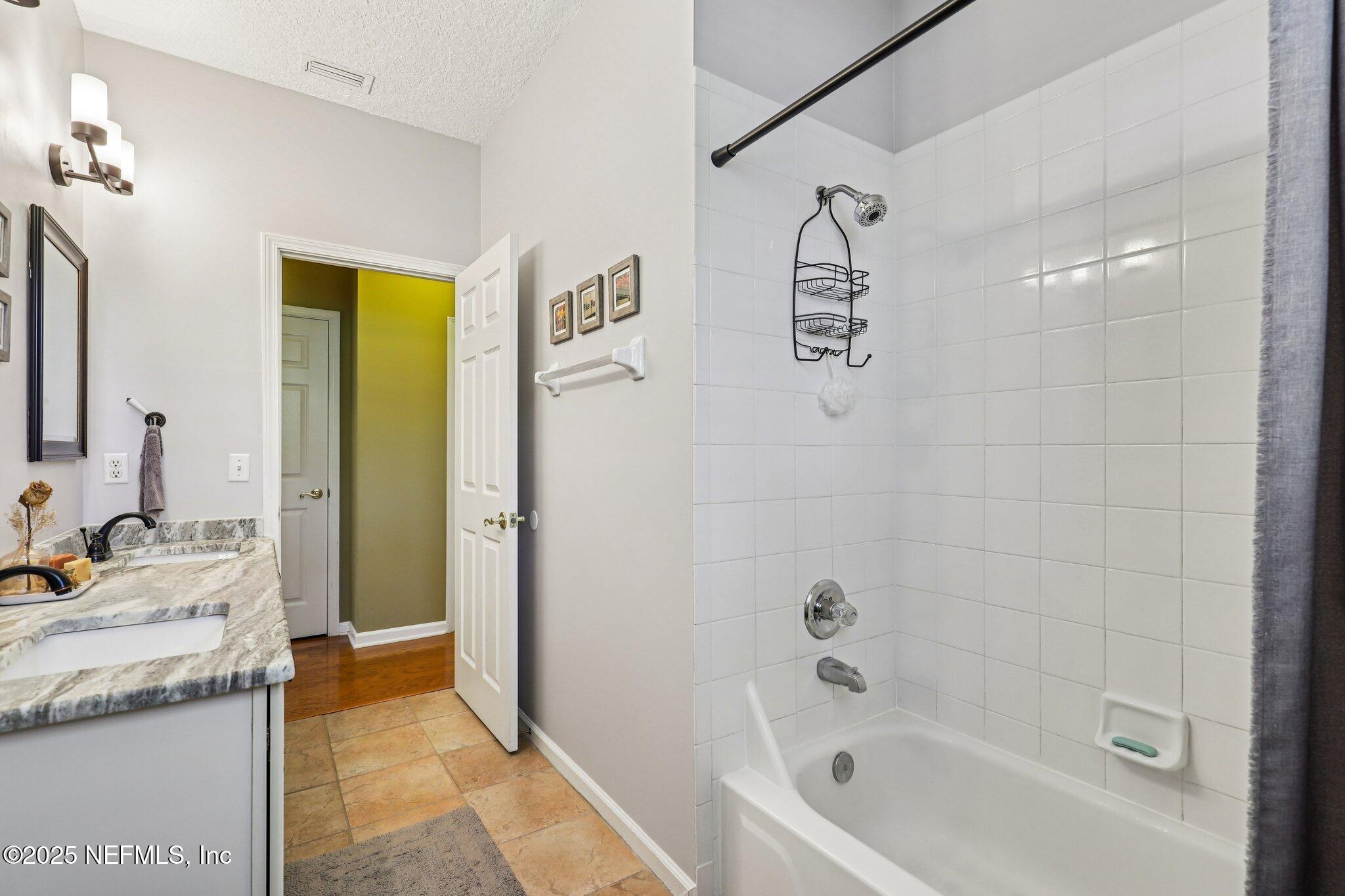 1432 Course View Drive Fleming Island, FL 32003 - Photo 38 of 83 a bathroom with a granite countertop sink a mirror a bathtub and shower
