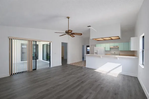 an empty room with wooden floor ceiling fan and windows