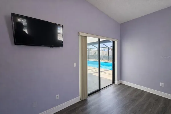 a view of an empty room with window and wooden floor