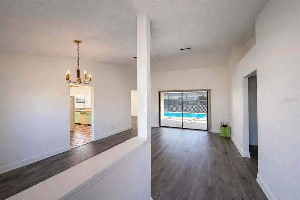 a hallway with wooden floor chandelier and entryway