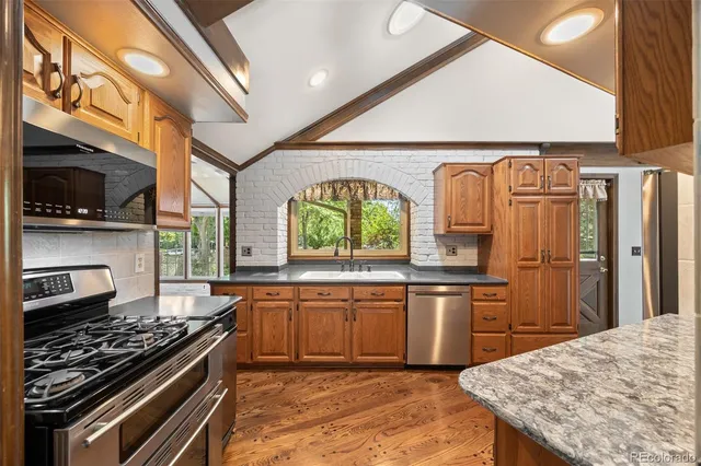 a kitchen with stainless steel appliances granite countertop a sink a stove and a refrigerator
