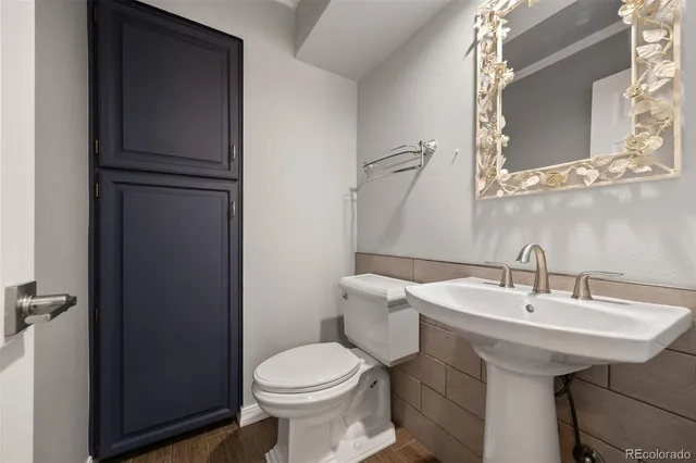 a view of an empty room with wooden floor and a kitchen
