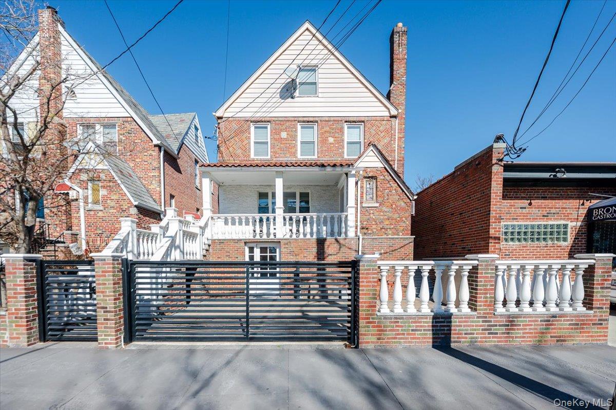View of front of property featuring brick siding, a porch, a fenced front yard, and a gate