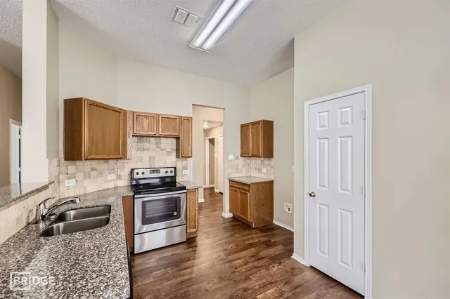 a kitchen with stainless steel appliances granite countertop a refrigerator stove and sink