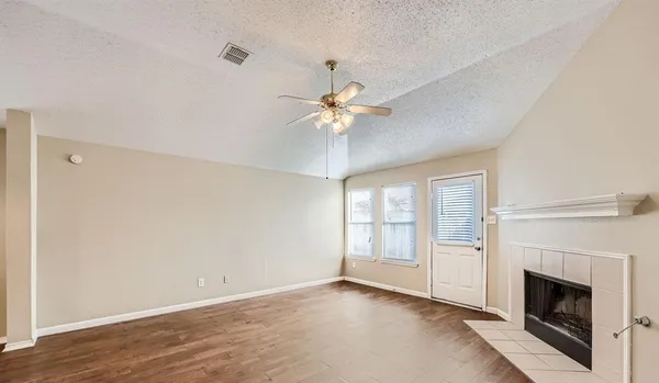 an empty room with chandelier fan and fireplace