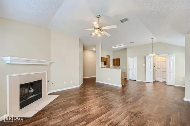 a view of a livingroom with a fireplace a ceiling fan and entryway