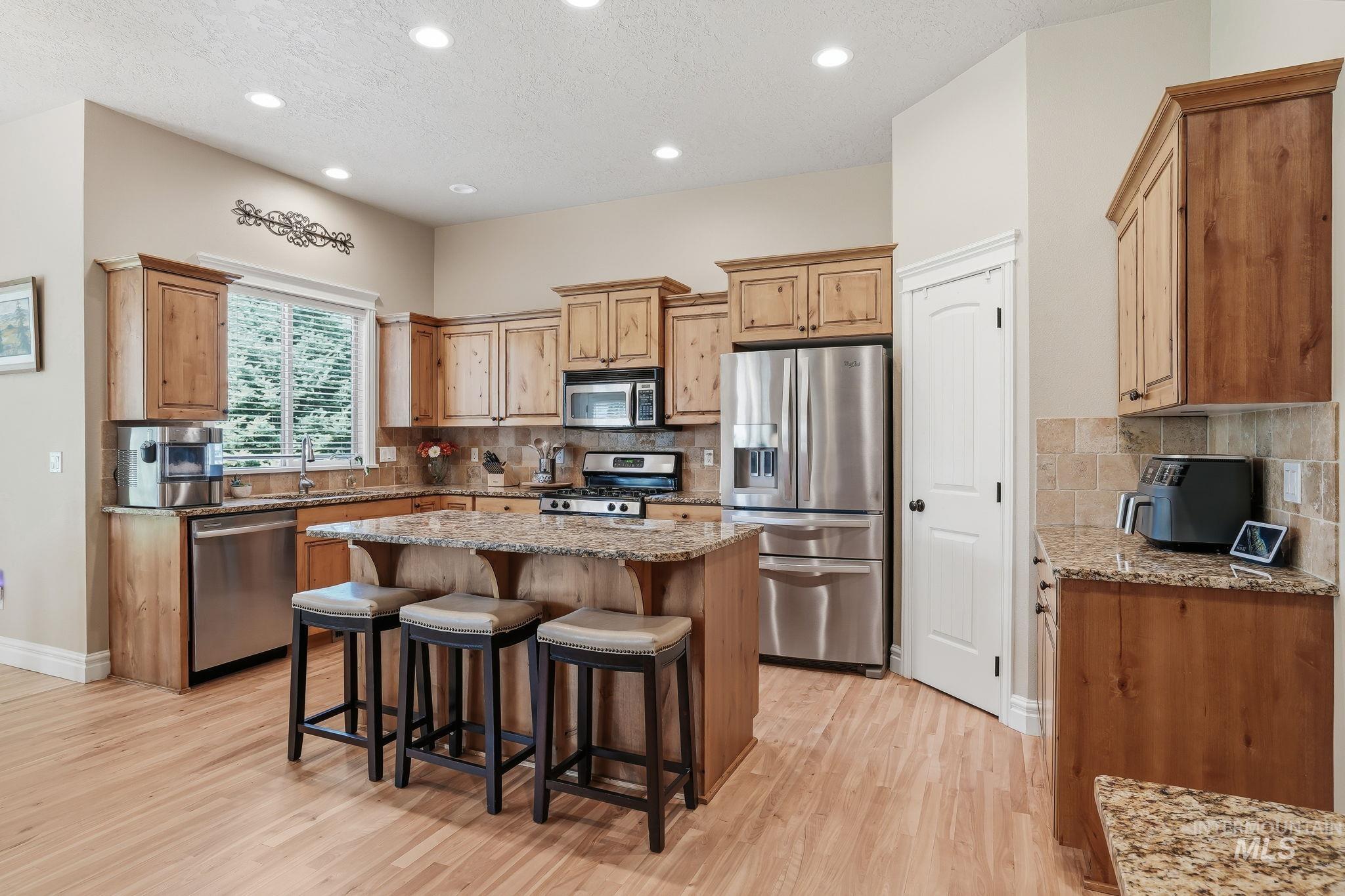 3969 North Hollymount Way Meridian, ID 83646 - Photo 10 of 47 Kitchen featuring wood-finish cabinetry, granite countertops, tile backsplash, and stainless steel appliances
