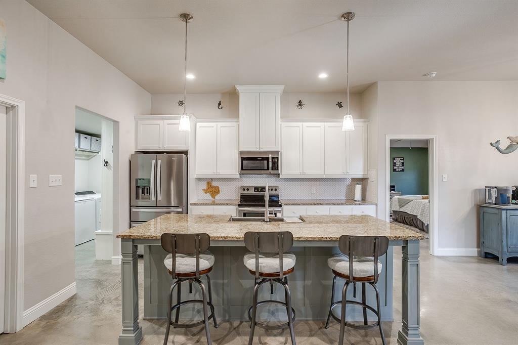 111 Treys Way Godley, TX 76044 - Photo 16 of 38 a kitchen with stainless steel appliances kitchen island granite countertop a dining table chairs refrigerator and sink