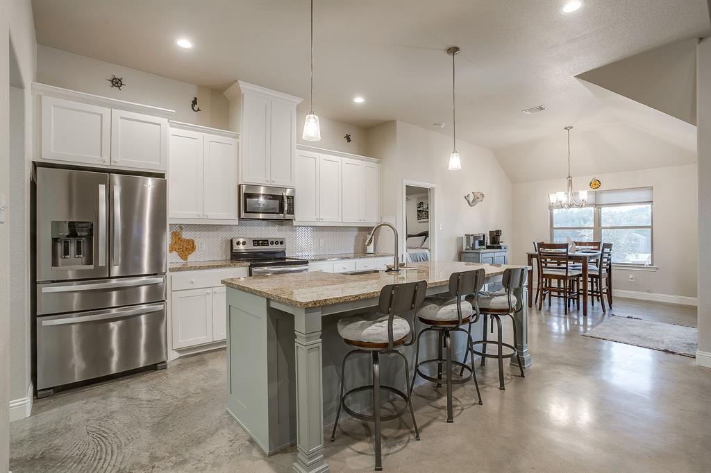111 Treys Way Godley, TX 76044 - Photo 17 of 38 a kitchen with stainless steel appliances kitchen island granite countertop a stove a refrigerator a oven a dining table and chairs with wooden floor