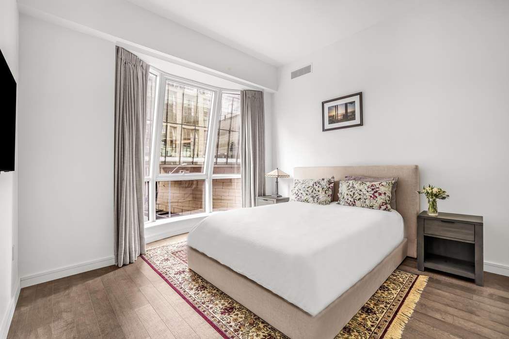 515 West 18th Street, Unit 308 Manhattan, NY 10011 - Photo 5 of 16 a large bed sitting in a bedroom next to a window