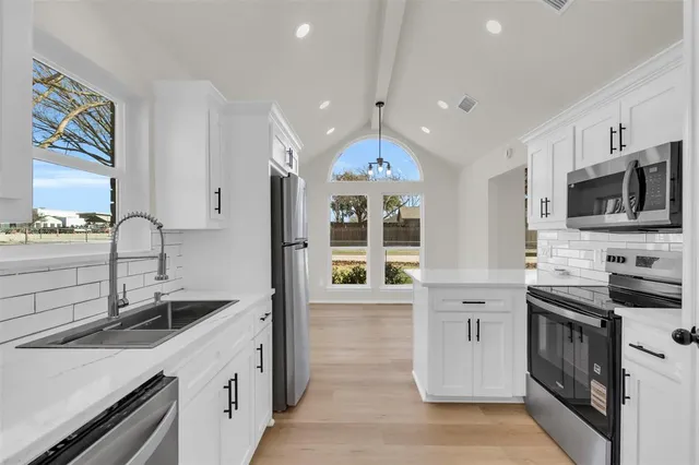 a kitchen with granite countertop a sink stainless steel appliances and cabinets