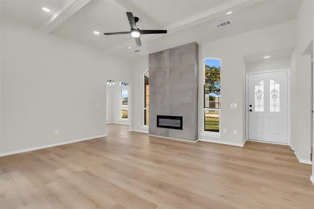 a view of an empty room with a window and wooden floor