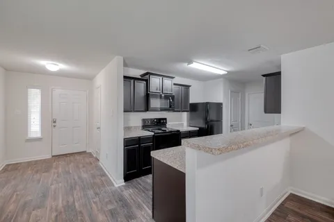 a kitchen with granite countertop a refrigerator stove top oven and sink
