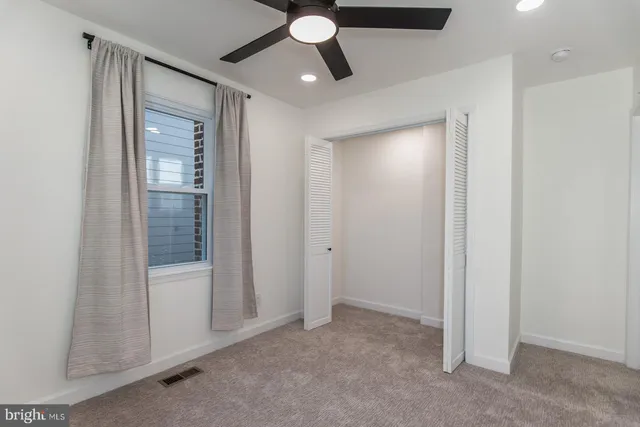 an empty room with windows and fan