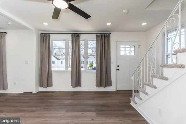 a view of a hallway with wooden floor and a kitchen