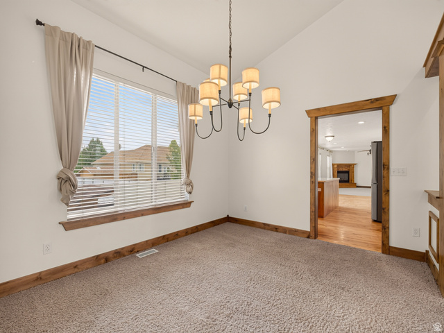 1279 West 1500th Street North Mapleton, UT 84664 - Photo 14 of 83 Carpeted room featuring a large window with blinds and drapes, a multi-arm chandelier, and a wood-trimmed doorway