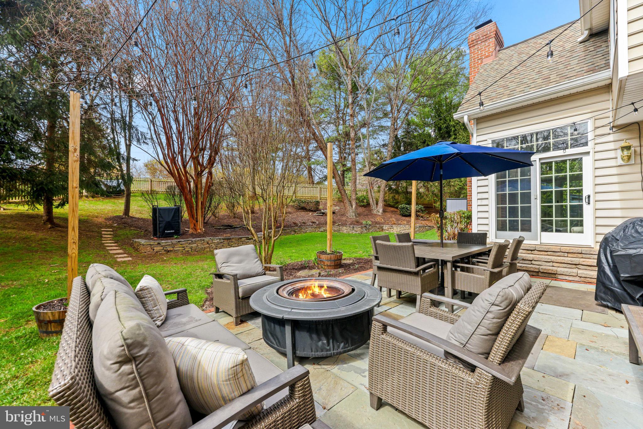 6513 Apple Blossom Ride Columbia, MD 21044 - Photo 102 of 115 a view of a patio with couches table and chairs under an umbrella with a large tree