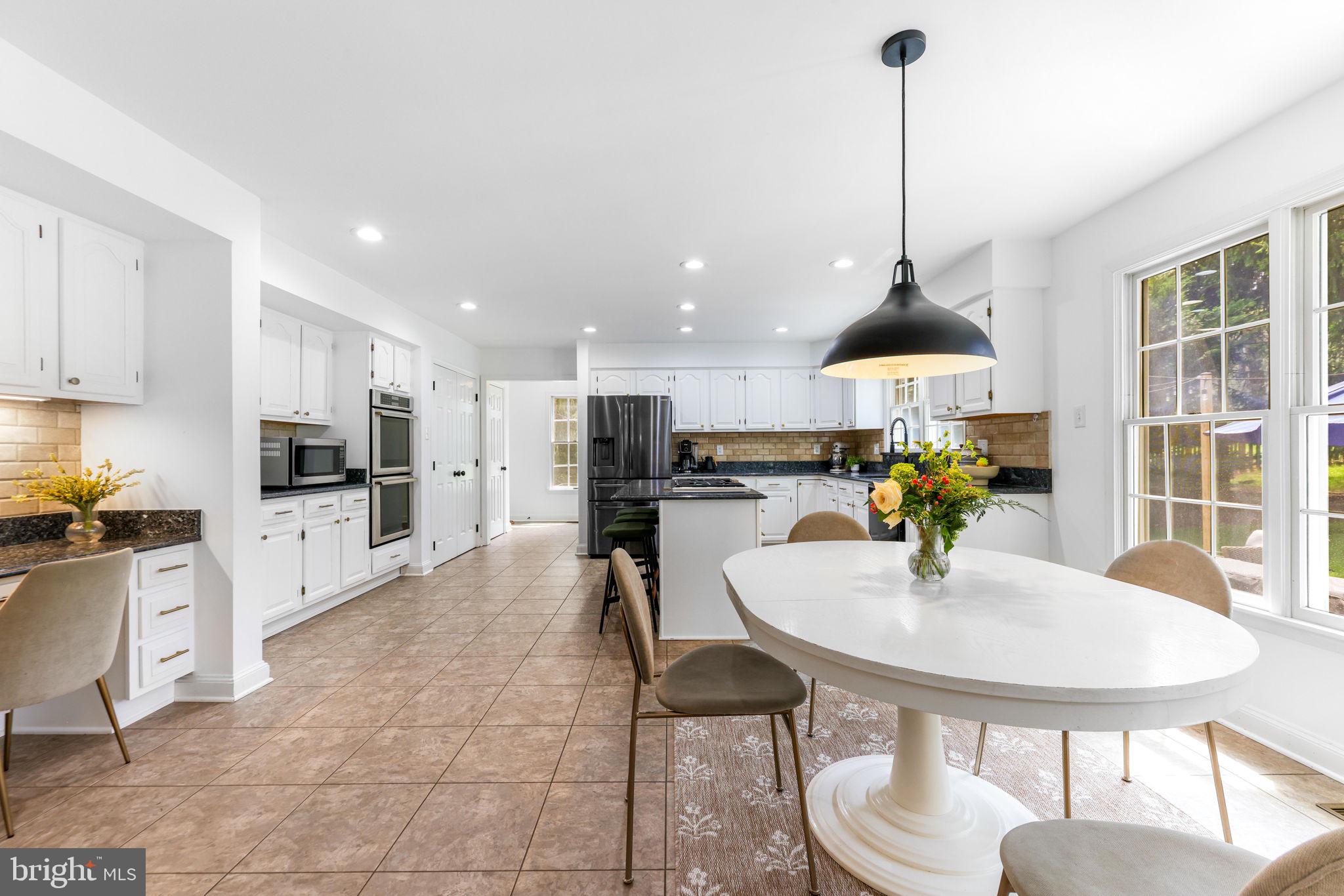6513 Apple Blossom Ride Columbia, MD 21044 - Photo 22 of 115 a kitchen with stainless steel appliances kitchen island granite countertop a dining table chairs and a stove