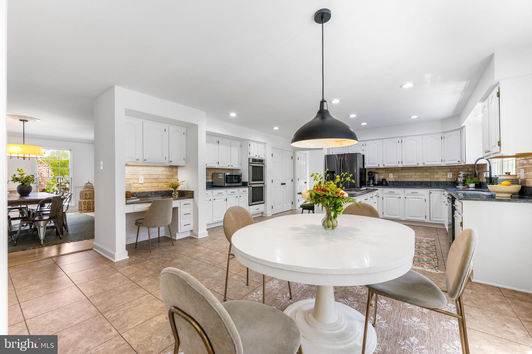 6513 Apple Blossom Ride Columbia, MD 21044 - Photo 23 of 115 a kitchen with stainless steel appliances kitchen island granite countertop a dining table chairs and white cabinets