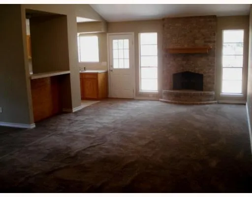 an empty room with windows and fireplace