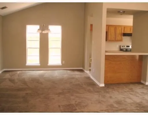 a view of an empty room with window and bathroom