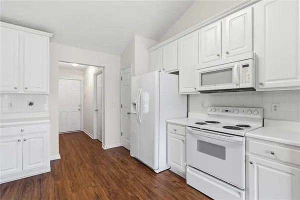 a kitchen with stainless steel appliances granite countertop a sink dishwasher stove and white cabinets with wooden floor