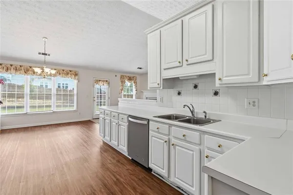 a kitchen with stainless steel appliances a stove top oven a sink a refrigerator white cabinets and wooden floor