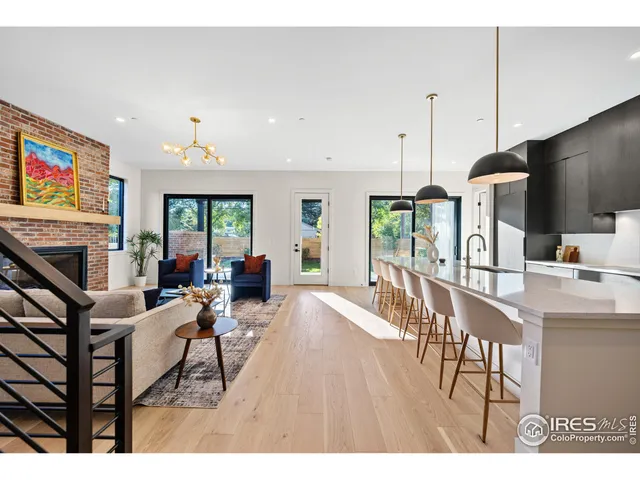 a kitchen with stainless steel appliances kitchen island granite countertop a dining table chairs and a refrigerator