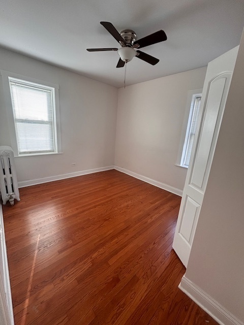 5521 West Farragut Avenue, Unit 3E Chicago, IL 60630 - Photo 8 of 12 an empty room with wooden floor fan and windows