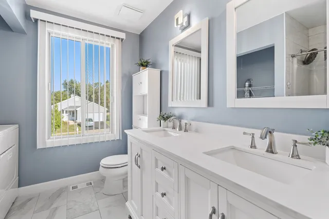 a bathroom with a double vanity sink toilet and a mirror