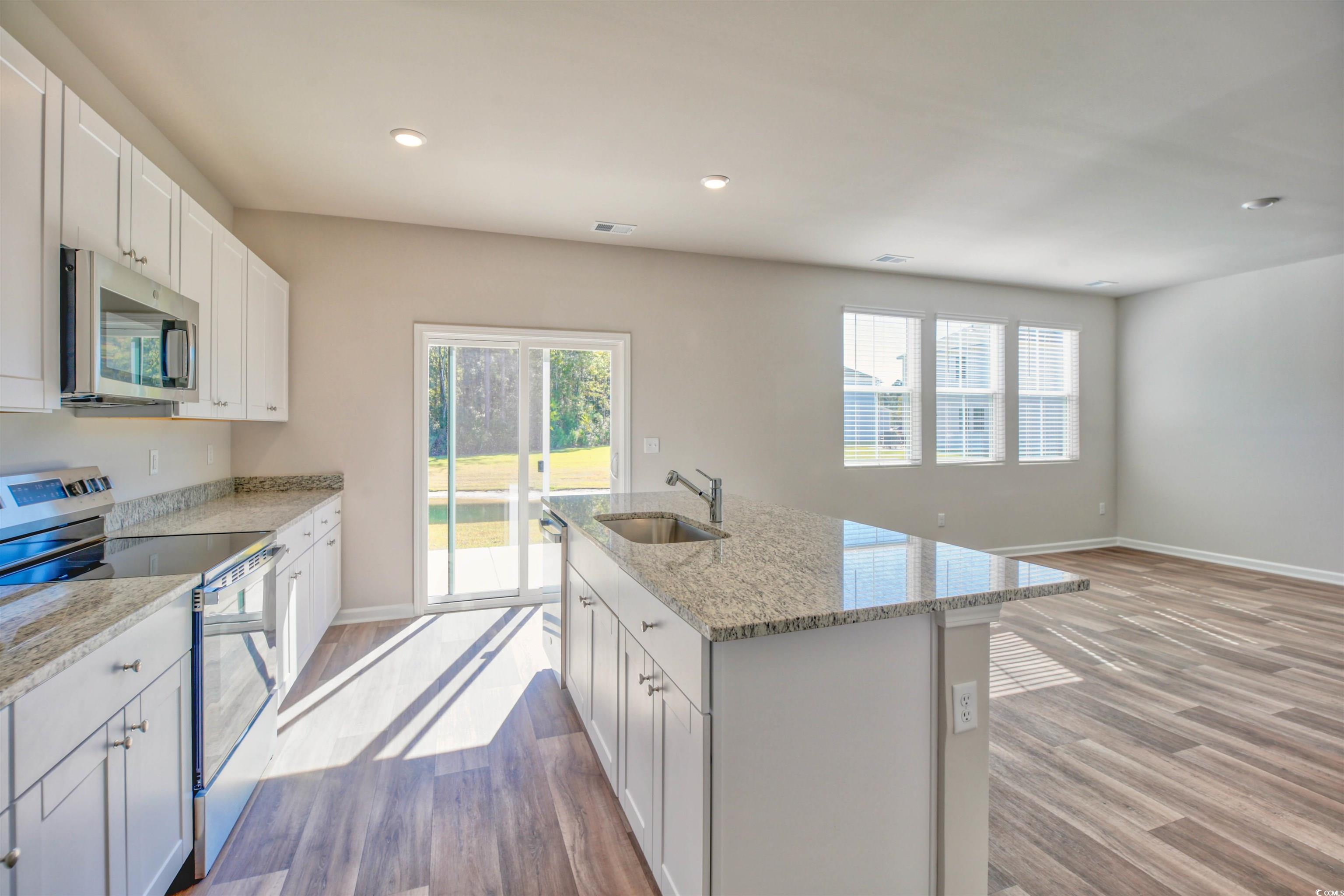 736 Sturdy Root Place Myrtle Beach, SC 29588 - Photo 14 of 15 Kitchen featuring stainless steel appliances, light stone counters, a center island with sink, white cabinets, and recessed lighting