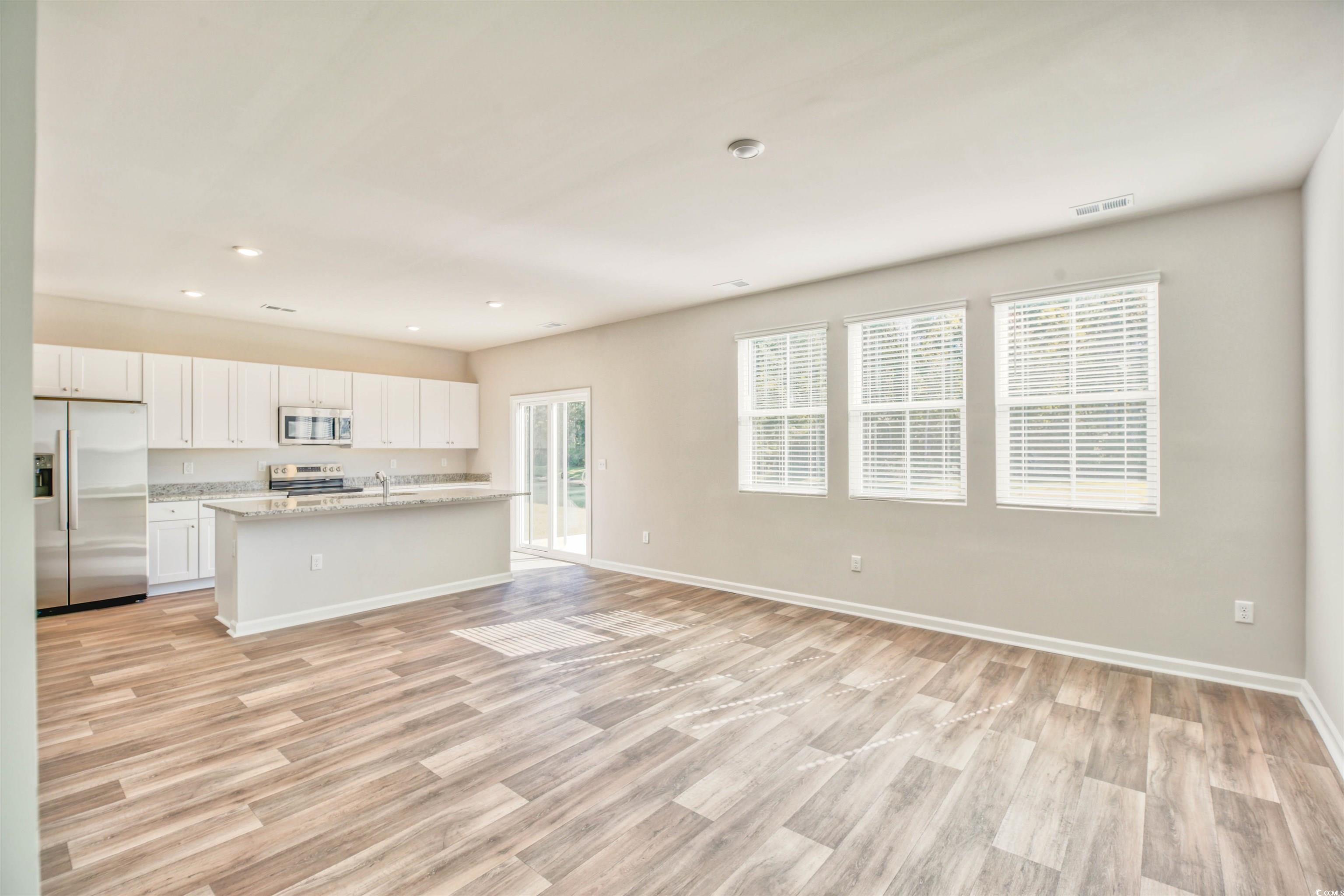 736 Sturdy Root Place Myrtle Beach, SC 29588 - Photo 15 of 15 Kitchen featuring a kitchen island with sink, white cabinetry, stainless steel appliances, open floor plan, and light wood-type flooring