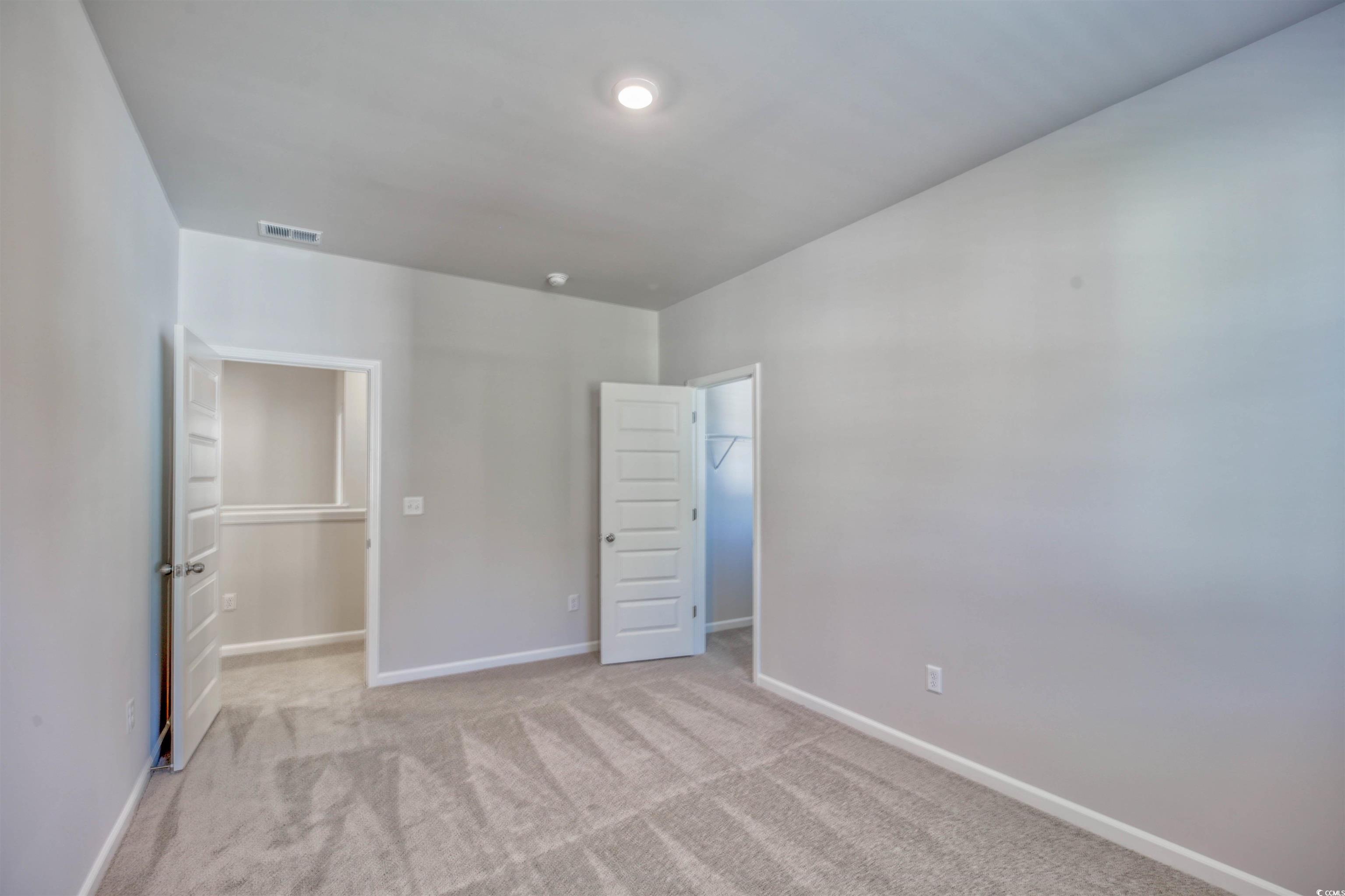 736 Sturdy Root Place Myrtle Beach, SC 29588 - Photo 4 of 15 Unfurnished bedroom featuring a walk in closet and light colored carpet