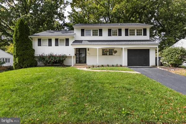 a front view of a house with a garden and trees
