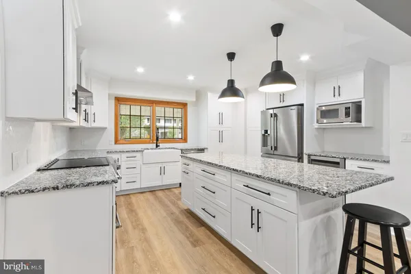 a kitchen with granite countertop kitchen island white cabinets and refrigerator
