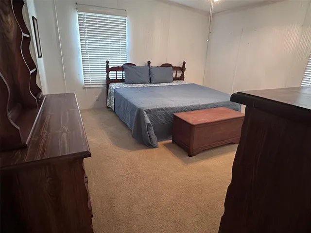 a bedroom with a bed and a flat tv screen on a dresser