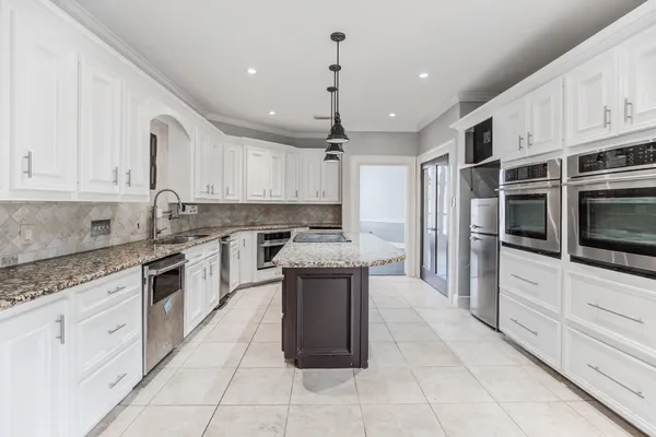 a kitchen with kitchen island granite countertop a stove sink and cabinets