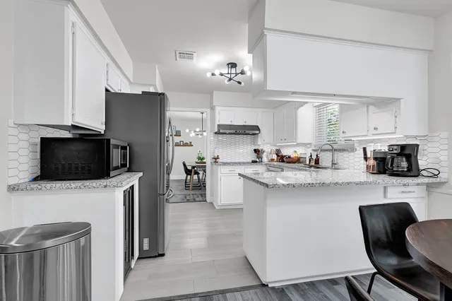 a kitchen with stainless steel appliances a stove a sink a microwave a refrigerator and cabinets