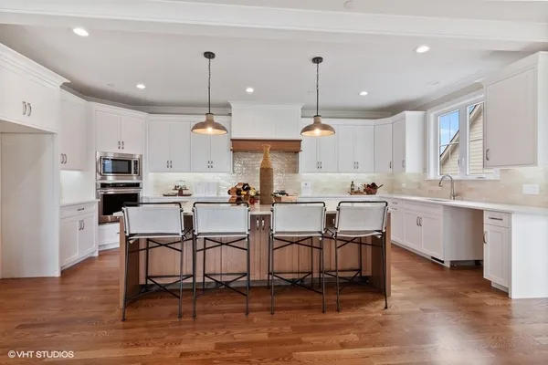 a kitchen with stainless steel appliances kitchen island granite countertop a table chairs and a sink