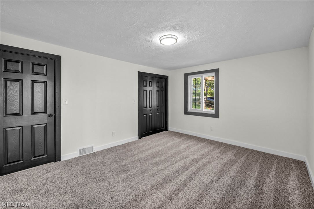 7339 River Road Olmsted Falls, OH 44138 - Photo 33 of 45 Carpeted room featuring light gray walls, dark paneled doors, and a ceiling-mounted light fixture
